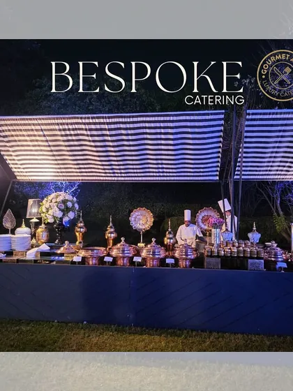 A "Bespoke Catering" buffet line under a striped canopy, showcasing our elegant copper serving dishes.
