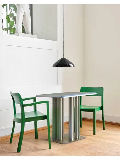 The XOXOX aluminum table, shown here in a minimalist dining nook, balances industrial strength with elegant aesthetics. Its polished metal legs and sleek tabletop make it a versatile piece for both contemporary indoor dining and outdoor settings.