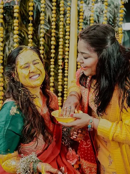 A sweet moment between sisters during the haldi. The genuine smiles and gentle application of turmeric paste show the love and bonding that these rituals are all about.