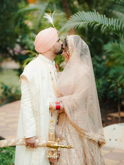 A tender forehead kiss. This portrait of a Sikh couple, with the groom holding a traditional kirpan, is both regal and romantic.