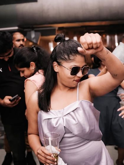 A partygoer with a drink in hand, completely in her element on the dance floor.