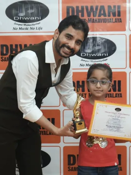 A teacher presents an award to a young student, encouraging her artistic journey.