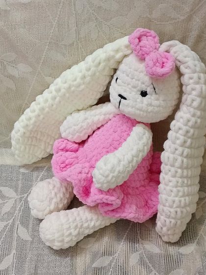A plush bunny with extra-long, floppy ears, dressed in a cute pink frock.