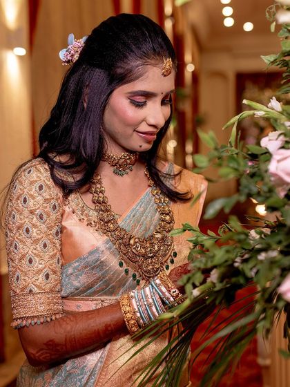 A bride posing with flowers, her soft-hued saree and delicate jewelry creating a romantic and feminine look.