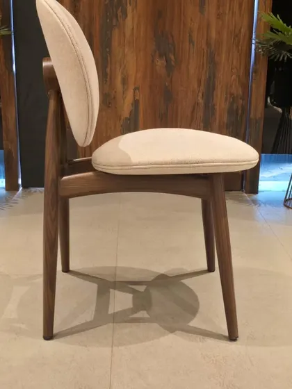 A side view of our fabric dining chair with a distinctive round backrest. The frame has a realistic wooden finish but is made of durable metal for extra strength.