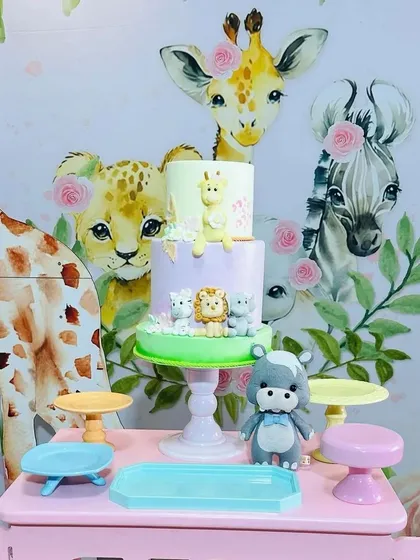 A close-up of the safari-themed cake, adorned with tiny, edible jungle animals, sitting perfectly on its stand atop the pink jeep table.