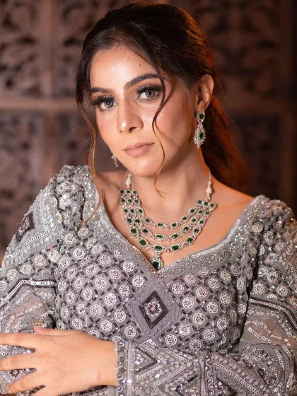 A poised shot highlighting the intricate work on the lehenga and the elegance of the layered necklace. This is a complete look available for rent.