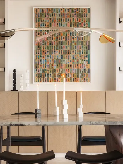 A detail of the dining table, with its unique base that is glass on one side and wood on the other. The custom candle holders on the table are small, sculptural art pieces.