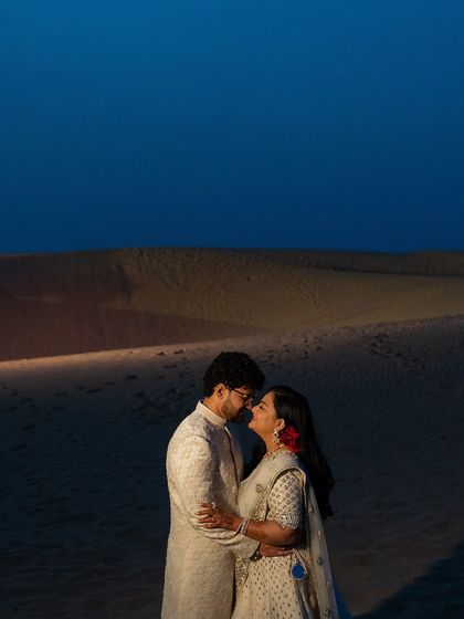 A romantic shot of the couple against the dramatic backdrop of the Jaisalmer sand dunes at dusk.