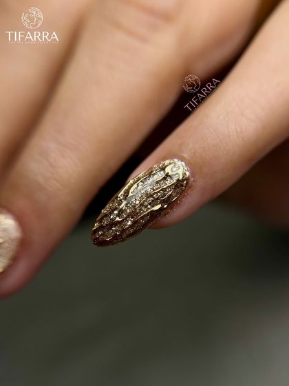 A textured, molten gold effect on an almond-shaped nail extension. This unique design adds a raw, artistic dimension to the luxurious gold finish.
