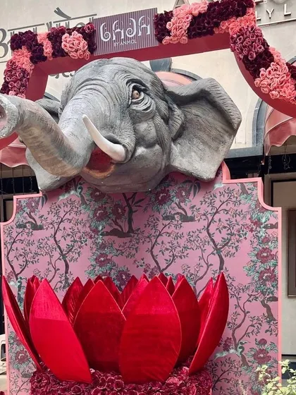 The full view of the elephant and lotus installation for Anmol Jewellers, framed by a floral arch in shades of pink.