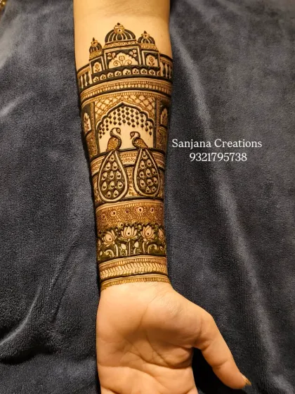 A close-up of the completed arm piece, with majestic peacocks inside a palace window, finished with a lotus band.