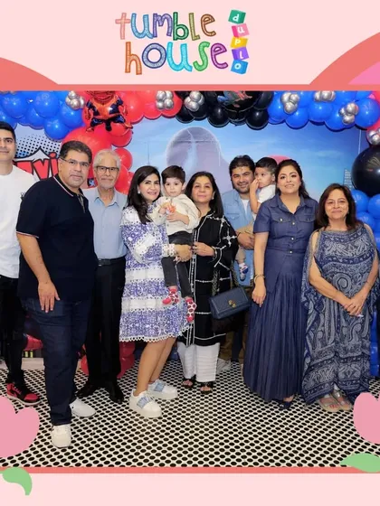 A large family group poses in front of a Spiderman-themed balloon arch. It's wonderful to see the whole family come together to celebrate.