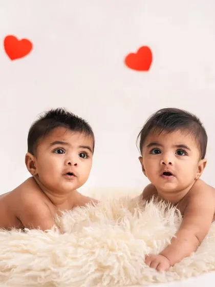 Twin brothers enjoying tummy time together on a soft, furry rug. This is a great pose for a 6-month milestone session.