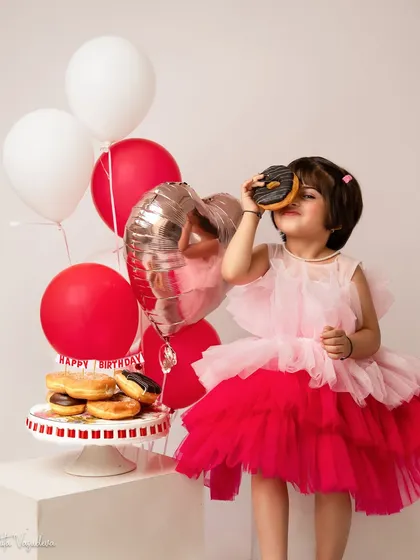 How sweet it is to be four. This little one is enjoying a donut from her birthday cake stand, a candid and adorable moment from her 4th birthday photoshoot.
