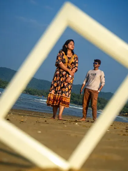 Getting creative with a pre-wedding shoot on a Goa beach. Using a simple white frame, I created a unique composition that draws the eye directly to the couple against the stunning backdrop of the sea and hills. I love finding artistic ways to make your photos stand out.