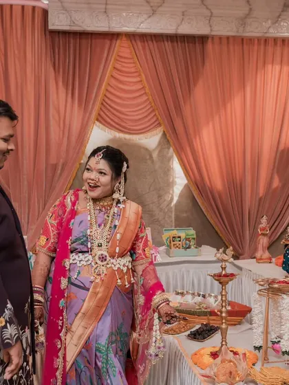 The happy parents-to-be, Kajal and her husband, admiring the traditional food table we set up for their baby shower.