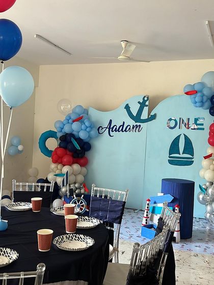 A classic sailor theme for Aadam's first birthday. The decor features a wave-shaped backdrop in shades of blue, with anchor and sailboat motifs, and perfectly coordinated table settings for the little guests.