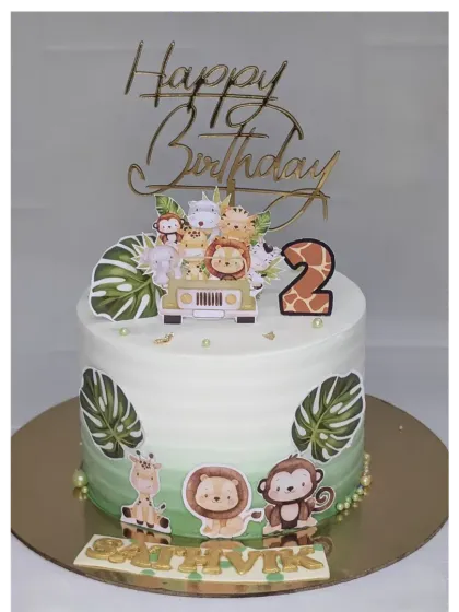 A jungle safari cake for a 2nd birthday. This chocolate truffle cake is decorated with cute animal toppers and monstera leaves, all without fondant.