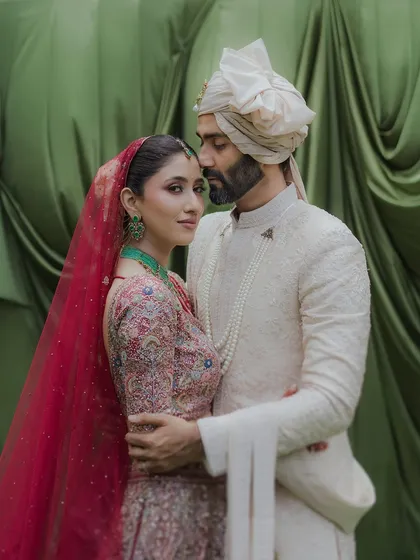 A classic portrait where the groom holds his bride close. Her gaze towards the camera and his towards her creates a beautiful dynamic, all set against a rich green backdrop at the Taj Lands End.