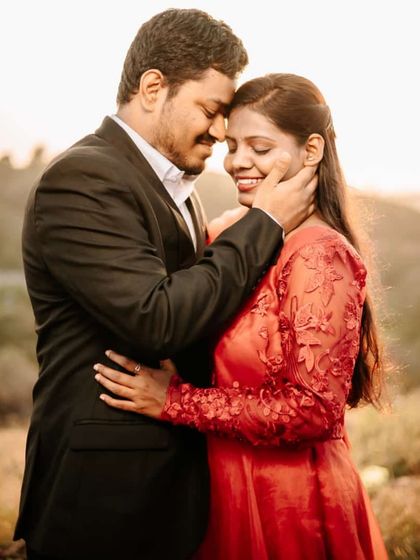 An intimate close-up filled with love and anticipation. The detailed embroidery on the sleeve of this red-orange gown adds a touch of elegance.