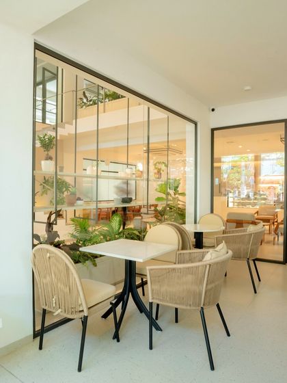 Our outdoor seating area, where you can enjoy your coffee surrounded by greenery. The glass walls blur the line between indoors and outdoors.