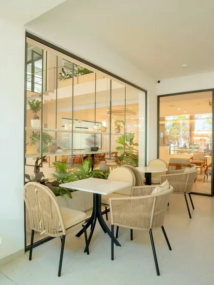 Our outdoor seating area, where you can enjoy your coffee surrounded by greenery. The glass walls blur the line between indoors and outdoors.