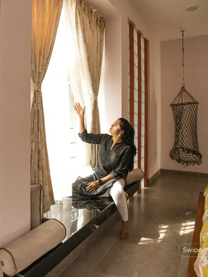 A resident enjoying the view from a large window with a built-in seat, a perfect example of creating comfortable nooks for relaxation.
