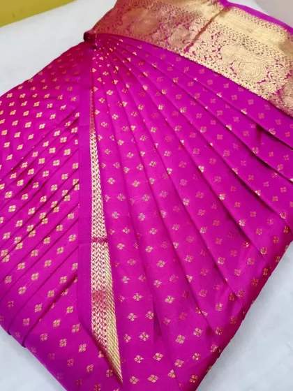 A bright pink silk saree with a gold border.