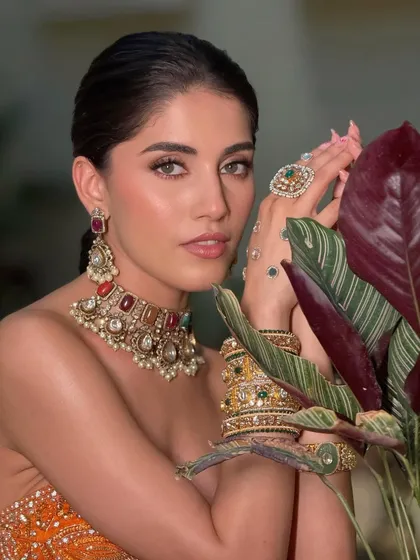 This boho-beautiful look is all in the quiet details. The makeup is breezy yet impactful, balancing the statement jewelry and vibrant orange lehenga.