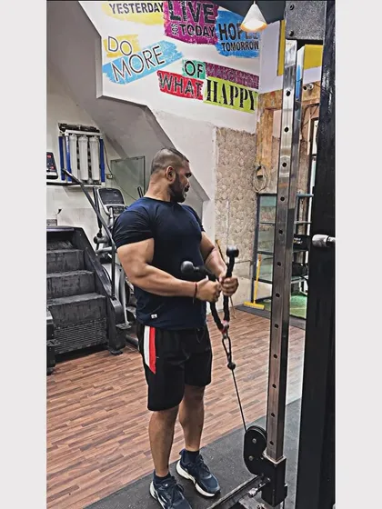 Using the cable machine for bicep curls. This exercise keeps constant tension on the muscle, helping to build that sought-after bicep peak.