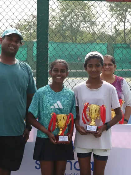 Trisha Bhosale and her doubles partner with their coach after winning the U-12 doubles title.