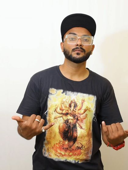 A classic pose against a white background. The Ganesha graphic on my shirt reflects my connection to my roots and culture, which I carry with me in my artistic journey.