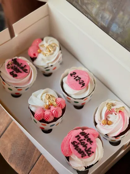 Another angle of the pink and white bridal shower cupcakes, showing the mix of piped frosting techniques and personalized details.