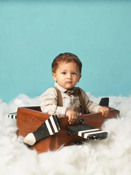 This little aviator is ready for takeoff, though he looks a bit serious about it! The wooden plane and cotton-ball clouds create a wonderful sky-high scene.