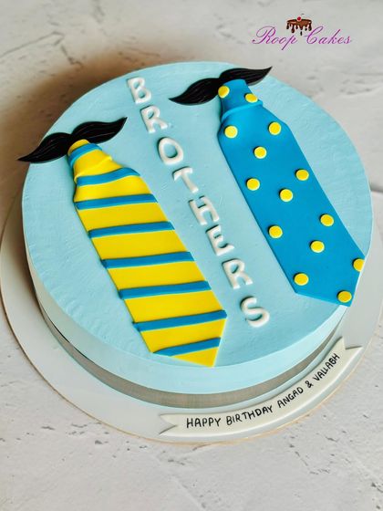 A clever cake for twin brothers. This design features two different neckties with mustaches, representing the unique personalities of each brother on their shared birthday.