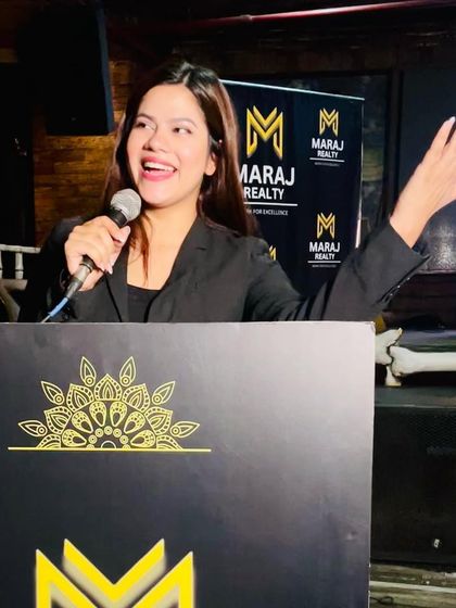 Engaging the audience with a big smile from the podium at a Maraj Realty event. My interactive style ensures no one feels like just a spectator.