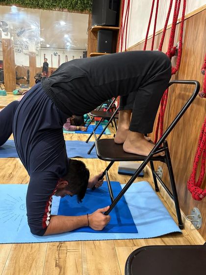 A side view of the chair-supported forearm backbend, showing how the prop helps create a beautiful arch in the spine while the student maintains control and stability.