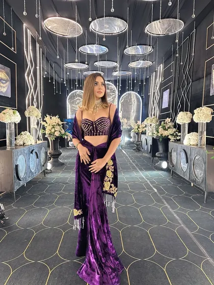 Another angle of the glamorous black and gold sangeet decor. This view highlights the custom side tables with white floral arrangements, which add a touch of softness to the modern, high-contrast design.