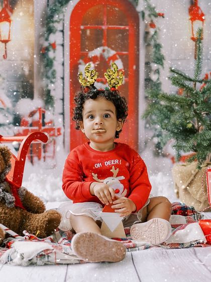 A little girl in a festive sweater and reindeer antlers, eating a snack. A real, candid moment from a holiday session.