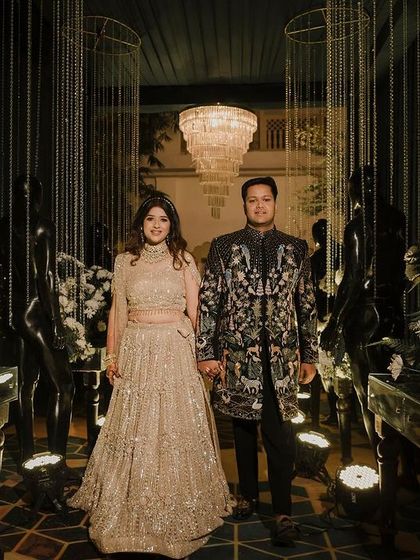 A glamorous Sangeet entrance featuring the couple framed by hanging crystal strings and lush white floral arrangements.