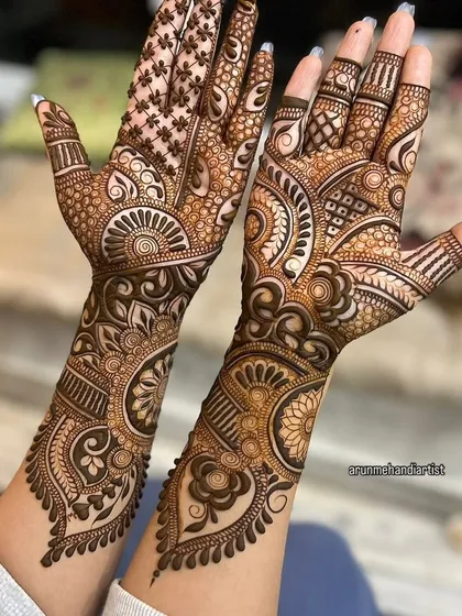 An elegant and flowing design that uses paisleys, semi-circular motifs, and delicate dot work. The pattern on the fingers complements the detailed work on the palms and wrists.