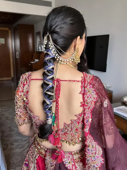 A vibrant and playful hairstyle perfect for a Mehendi or Haldi ceremony. This look features a thick braid intricately woven with colorful threads and finished with bright tassels and traditional hair jewellery, reflecting a fun and festive mood.