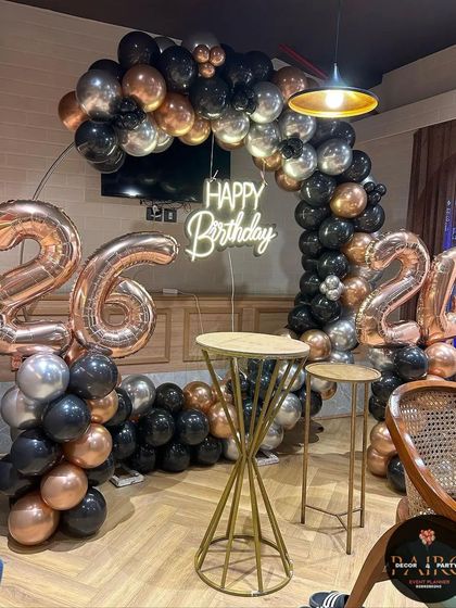 A stylish black, silver, and rose gold balloon ring decoration for a 26th birthday celebration in a modern space.