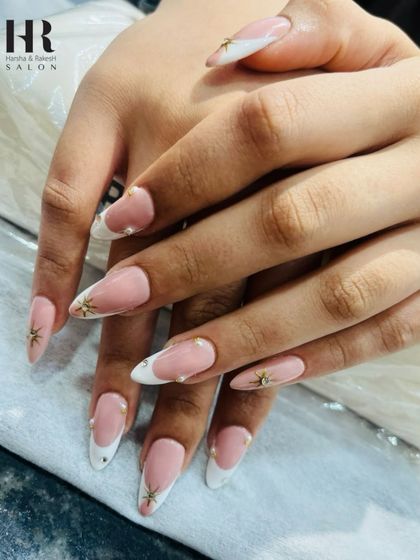 An elegant and timeless French manicure with a twist. This design features classic white tips on a natural pink base, accented with tiny gold starbursts and pearls for a subtle touch of glamour.