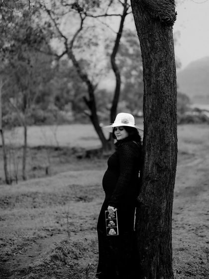 A classic black and white portrait of the mom-to-be leaning against a tree, holding her sonogram pictures. It’s a timeless and emotional image.