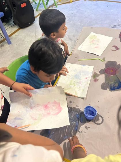A close-up of two boys engaged in a bubble painting art project. This activity is great for developing fine motor skills and learning about cause and effect.