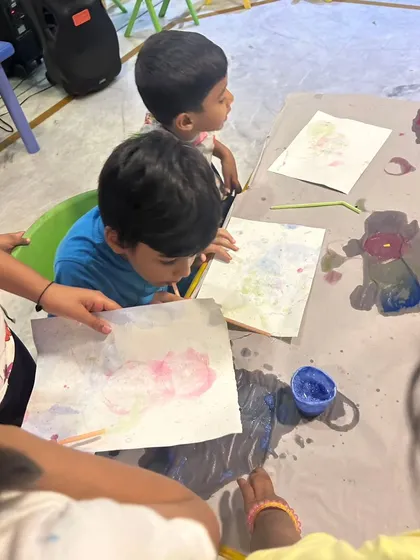 A close-up of two boys engaged in a bubble painting art project. This activity is great for developing fine motor skills and learning about cause and effect.