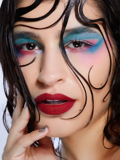 A colorful, painterly eye makeup look with a wet-look hairstyle, demonstrating a high level of artistic skill.
