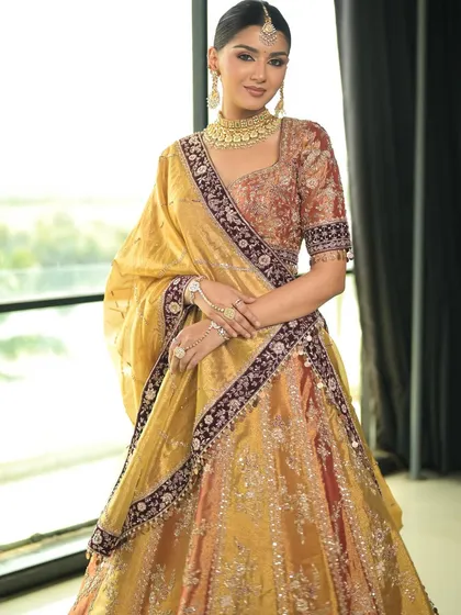 A full view of this stunning traditional bride. The makeup is perfectly balanced to complement the vibrant colors and heavy embroidery of her lehenga.